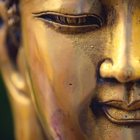 close up of a golden colored buddha head on black background ; China